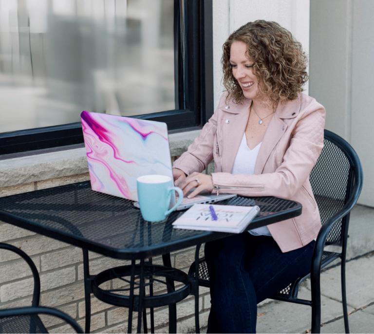 Picture of me sitting outside at a table working on my laptop, smiling