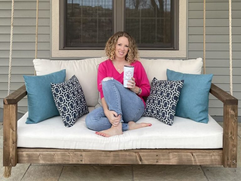 photo of me in a magenta sweater, sitting on a porch swing, holding a mug with the Complement Logo